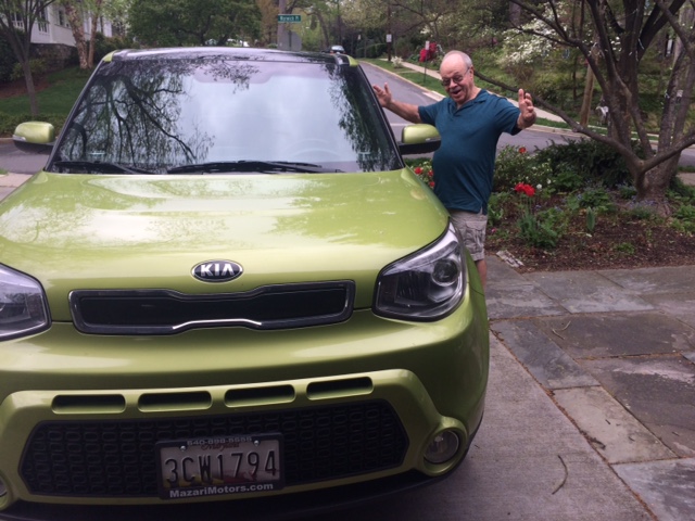 Frank S. Joseph standing beside his green Kia Soul with his arms outstretched